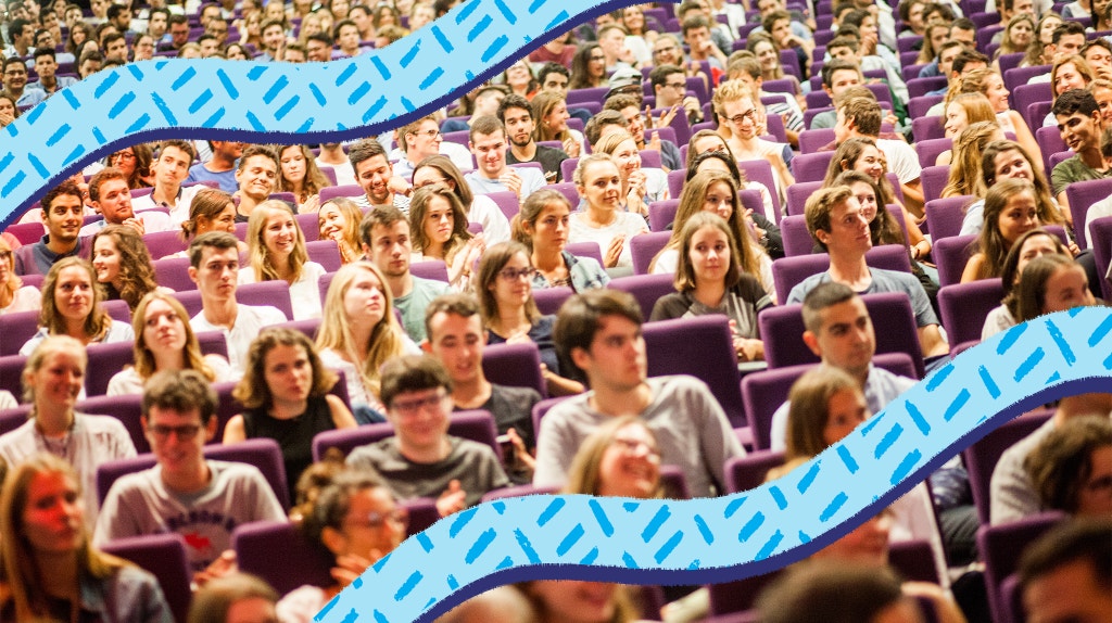 A full lecture hall of students watching their professor.