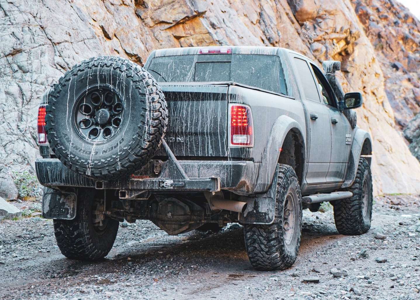 A black truck coated in mud and dust from a fun day out in the dirt.